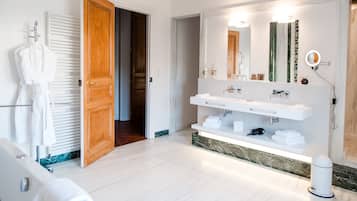 A modern bathroom with a double sink, a large mirror, and a robe rack.