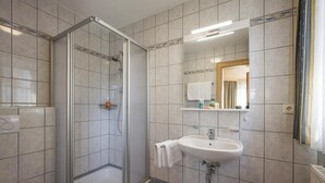 Un baño moderno con ducha envuelta en vidrio, un lavamanos blanco y un espejo encima.