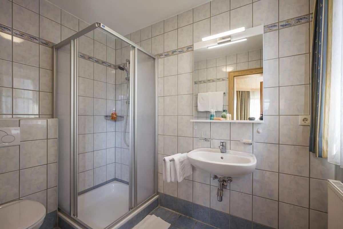 A modern bathroom with a glass-enclosed shower, a white sink, and a mirror above it.