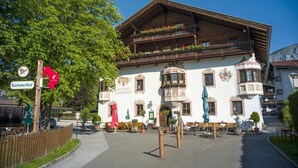 Un edificio de madera tradicional con un balcón, un letrero que dice 'Gasthaus Kämmerhof' y asientos al aire libre.