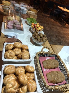 A buffet table with various food items including bread, fruits, and pastries. - Gasthaus Kammerhof (Angath)