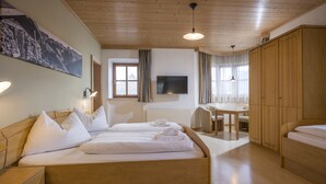 Una habitación de hotel con una cama de madera, un escritorio, una silla, un televisor y un armario.