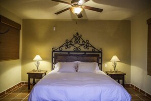 A bedroom with a wooden headboard, two bedside lamps, and a ceiling fan.