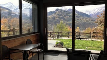 A room with a large window offering a view of mountains and autumn foliage.