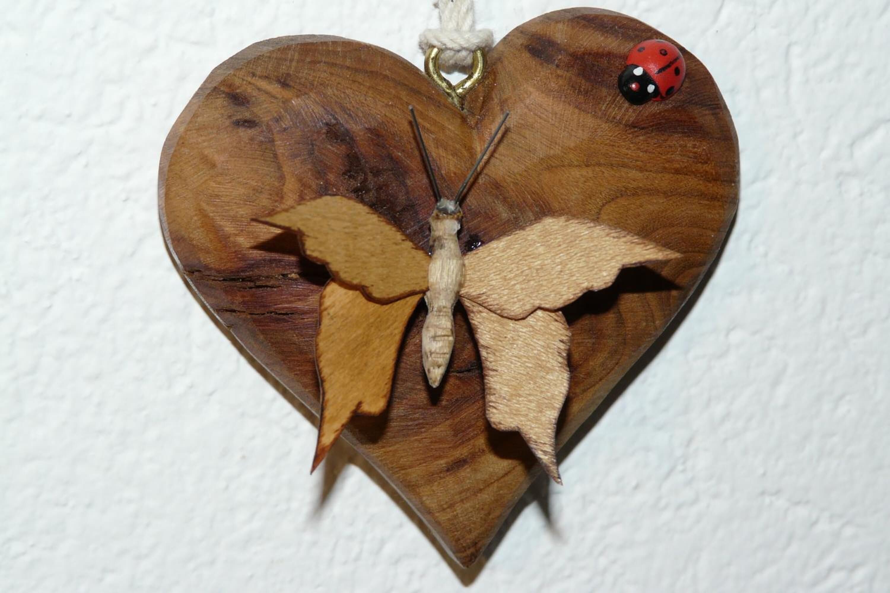 Una decoració de cor de fusta amb una papallona i un escarabat.