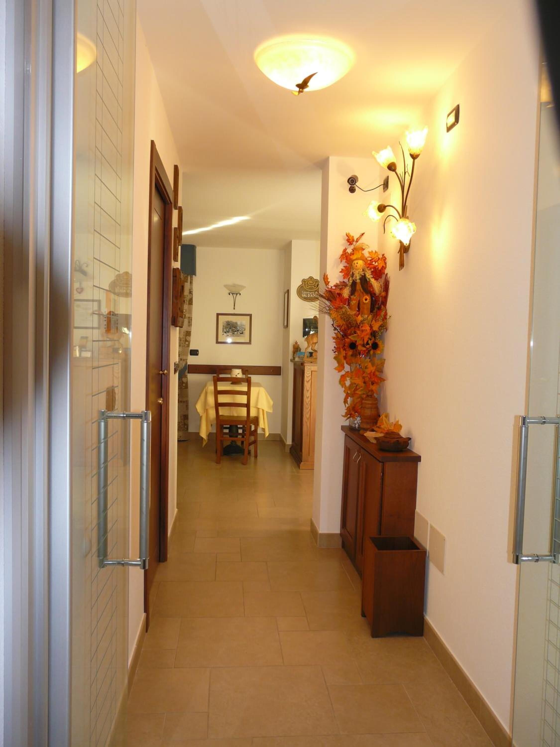 A hallway with a dining area in the background, a decorative wall piece, and a ceiling light.