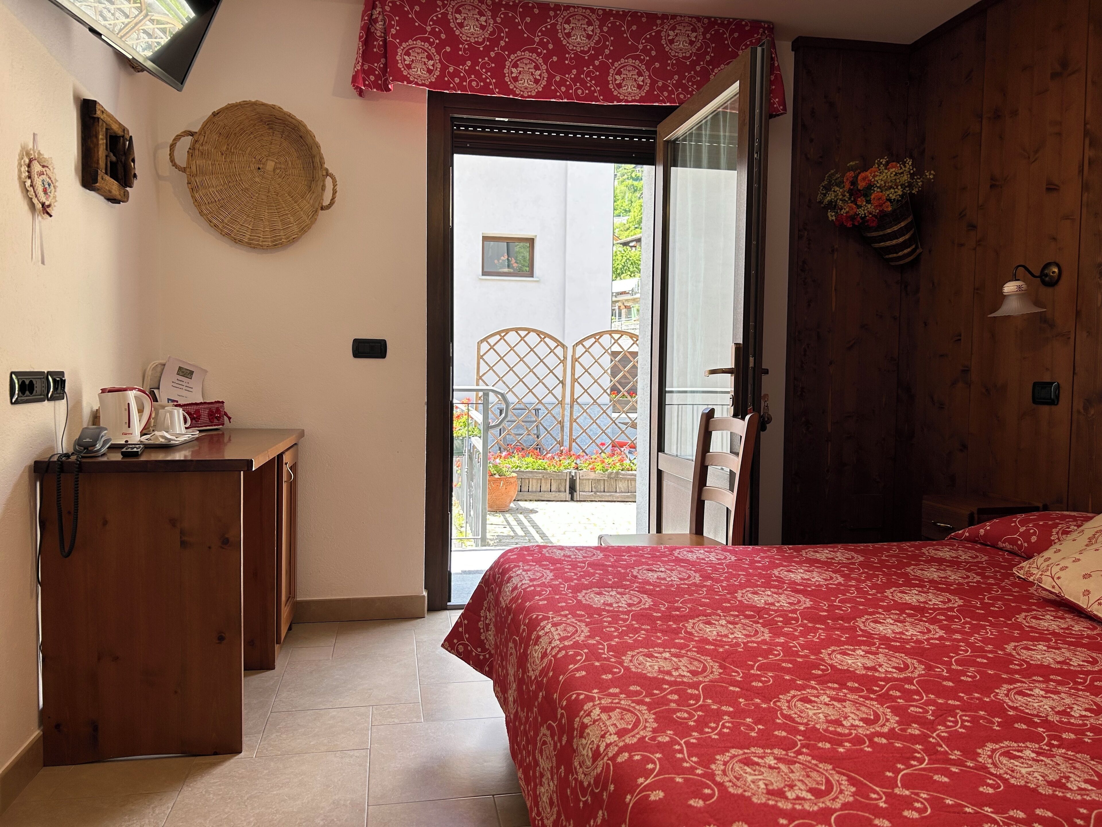 A bedroom with a bed, a desk, a chair, a window, and a view of the outside.