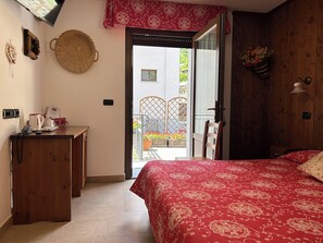 Une chambre à coucher avec un lit, un bureau, une chaise, une fenêtre et une vue sur l’extérieur.