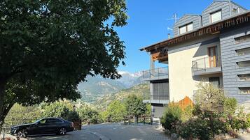 A modern building with a reception area, a parked car, and a mountainous backdrop.