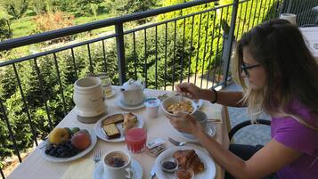 A balcony table with breakfast items including bread, fruit, and coffee.