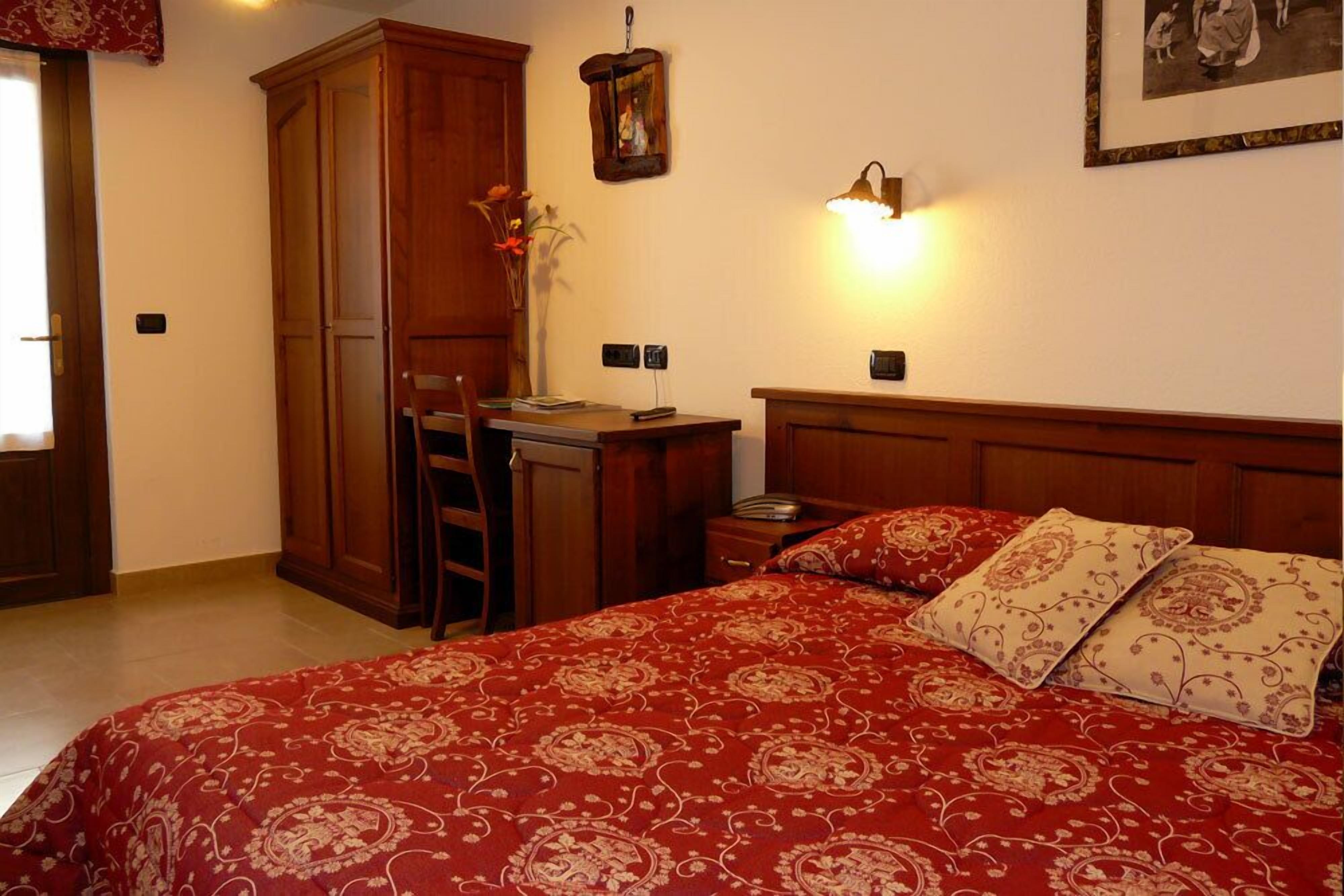 A bedroom with a large bed, a desk, and a wardrobe.