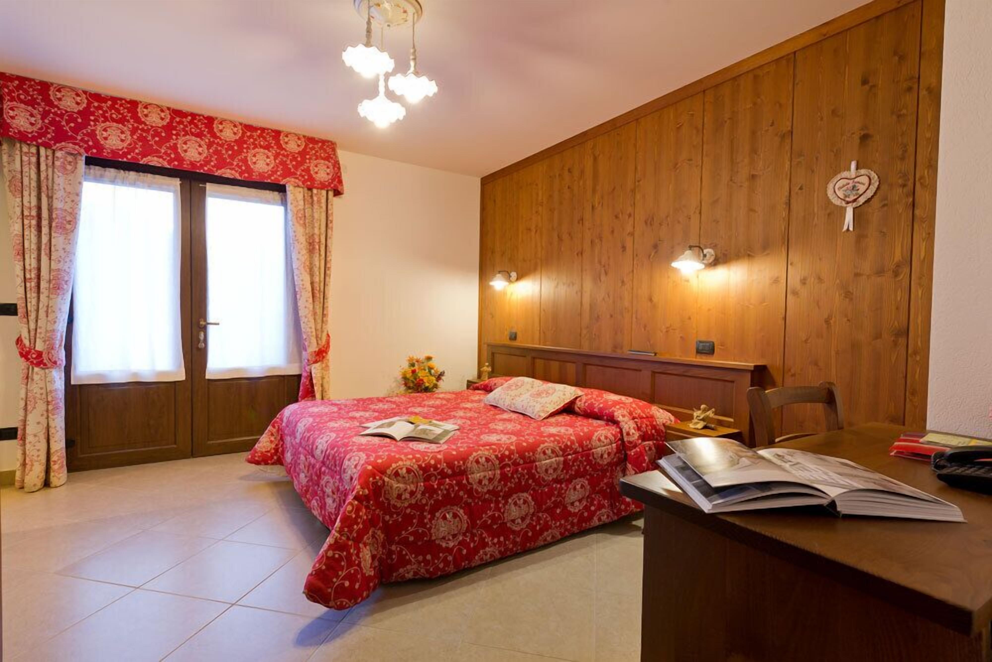 A bedroom with a bed, a desk, and a wooden wall panel.