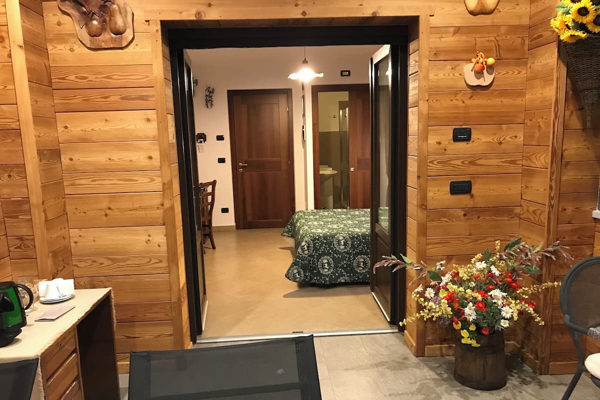 Un intérieur en bois comprenant un lit, une chaise et une table avec une bouilloire.