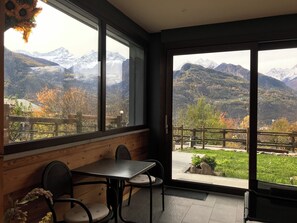 Une pièce avec vue sur les montagnes, un banc en bois et une table avec des chaises.