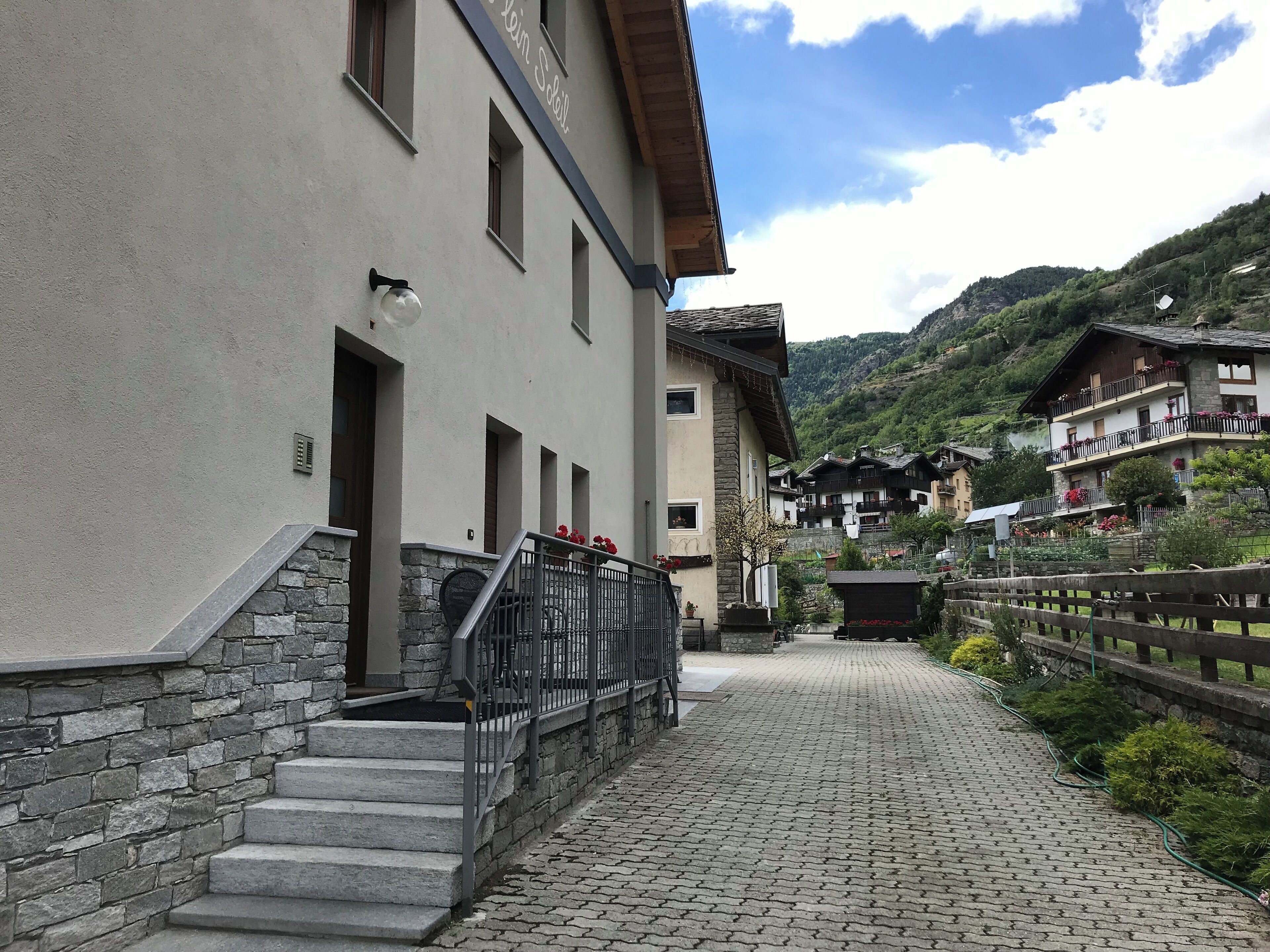 Una calle empedrada que conduce a un edificio con una escalera de piedra y una barandilla metálica.