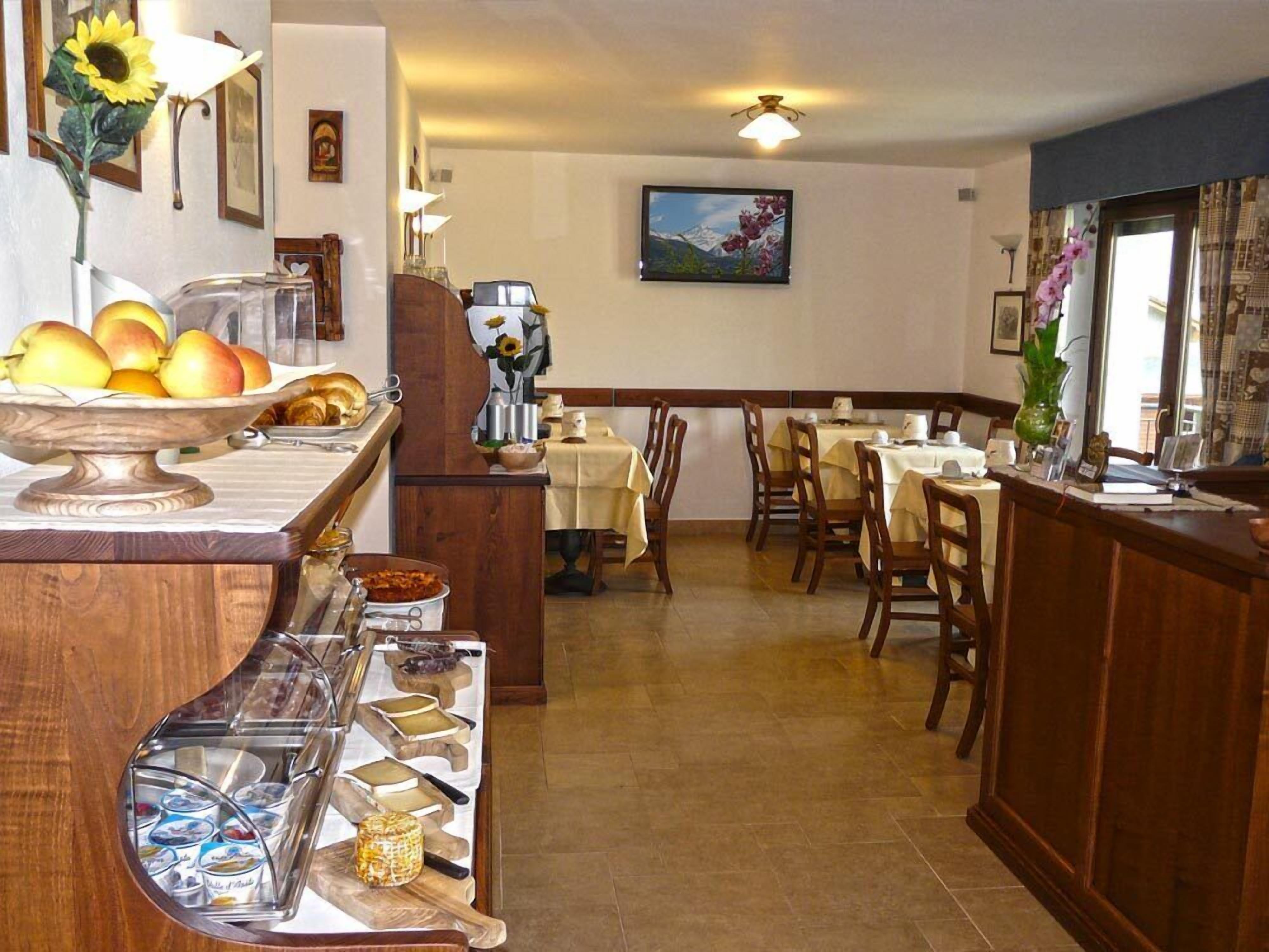 A restaurant with a wooden counter, tables, chairs, and a painting on the wall.