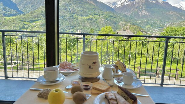 A table with breakfast items and a scenic mountain view. - B&B Verger Plein Soleil (Saint-Pierre)
