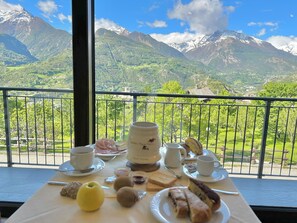 A table with breakfast items and a scenic mountain view. - B&B Verger Plein Soleil (Saint-Pierre)