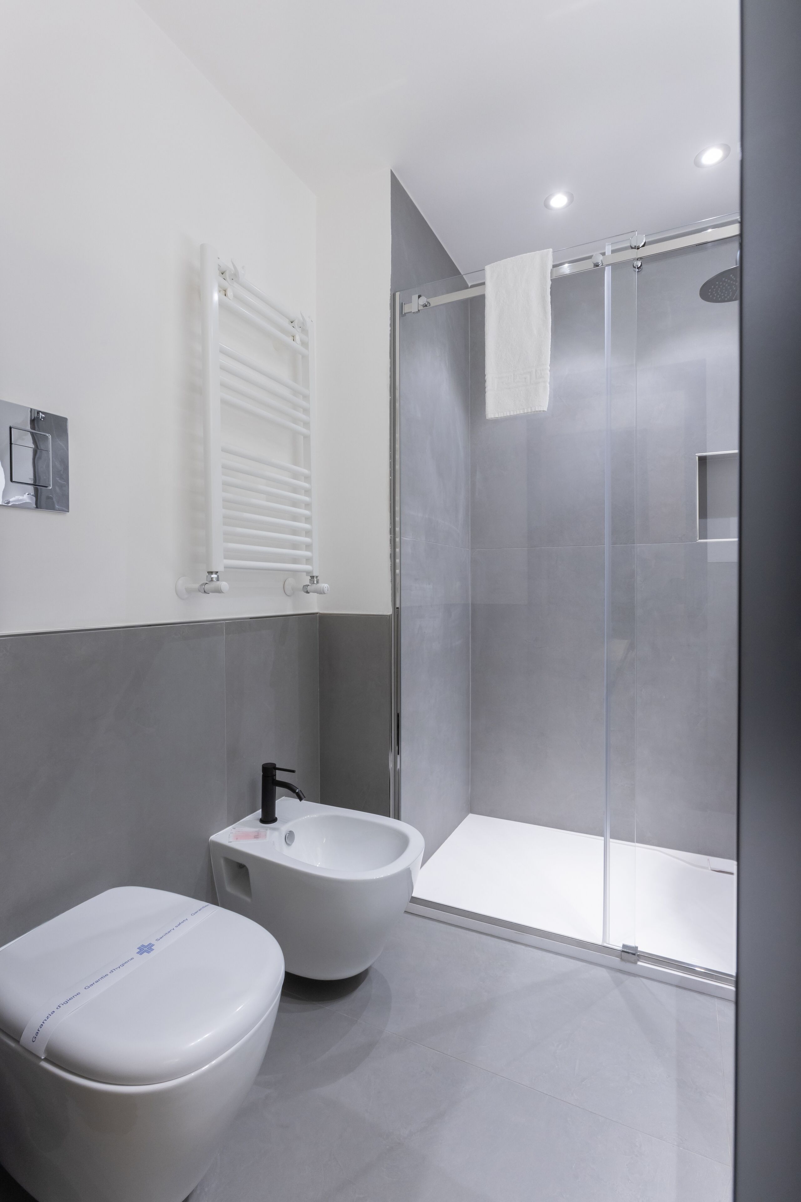 A modern bathroom with a toilet, bidet, and glass-enclosed shower.