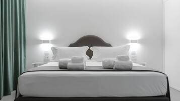 A neatly made bed with white linens and two pillows, flanked by two bedside lamps.