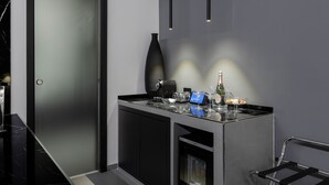 A modern, minimalist bar area with a sleek black and grey color scheme, featuring a coffee machine, a vase, and a wine bottle. - Suite Palermo Apartment (Palermo)