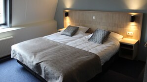 Een slaapkamer met een groot bed, twee nachtkastjes en een raam.