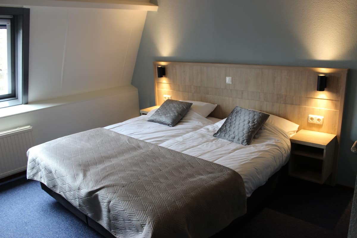Un dormitorio con una cama grande, dos mesitas de noche y una ventana.