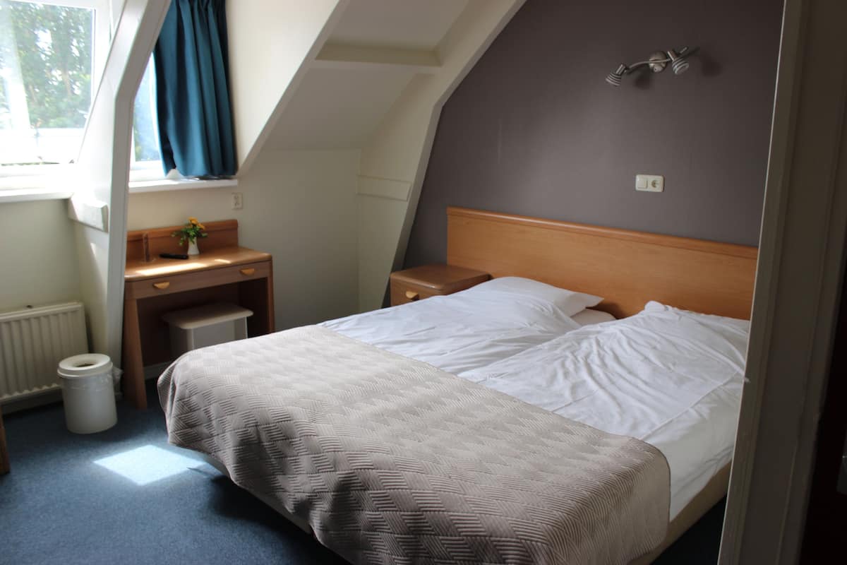 Un dormitorio con una cama, un escritorio y una ventana con cortinas.
