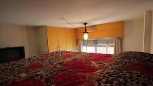 Une chambre avec un grand lit, un ventilateur de plafond et une fenêtre avec des rideaux.