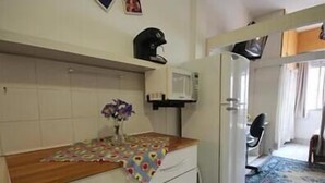 Une cuisine compacte équipée d’un four à micro-ondes, d’un réfrigérateur et d’un petit coin repas.