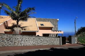 Situated on a slope, this property features a stone wall and a tiled roof with a skylight, offering a view of the horizon.