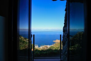 Vista da un balcone su un paesaggio costiero sotto un cielo sereno.