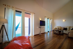 Relax in this spacious living room with a large bed, flat-screen TV, and comfortable leather sofa.
