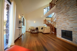 Relax in this inviting living area with a high ceiling, stone accent wall, and cozy fireplace.