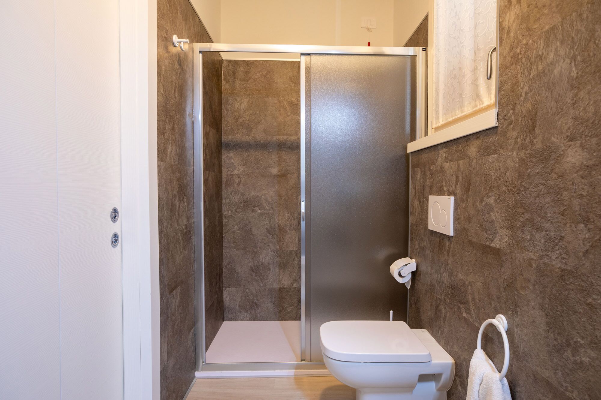 Ein Badezimmer mit Duschkabine, Toilette und Handtuchhalter.