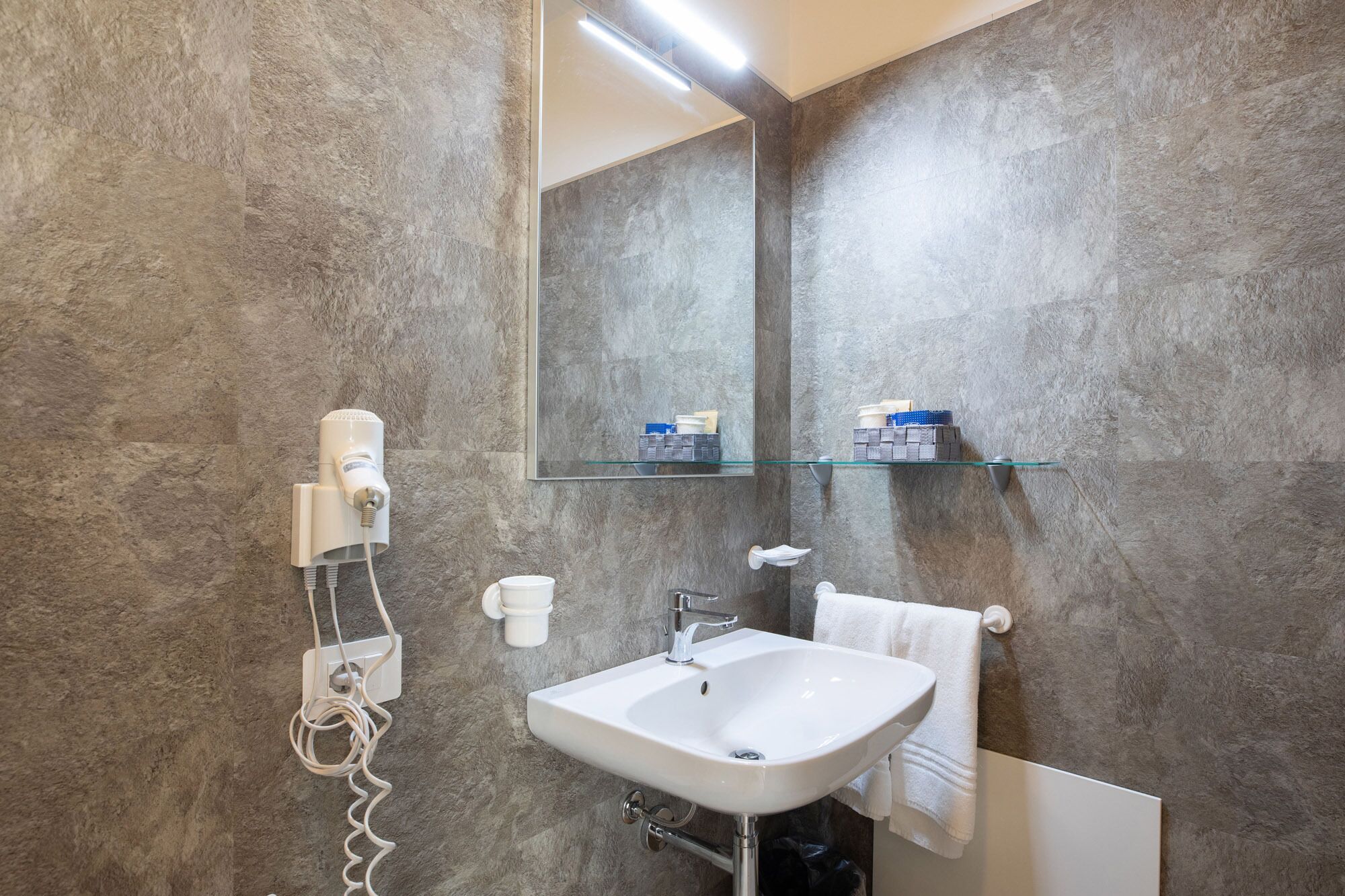 Een badkamer met een witte wastafel, een spiegel en een handdoekhouder.