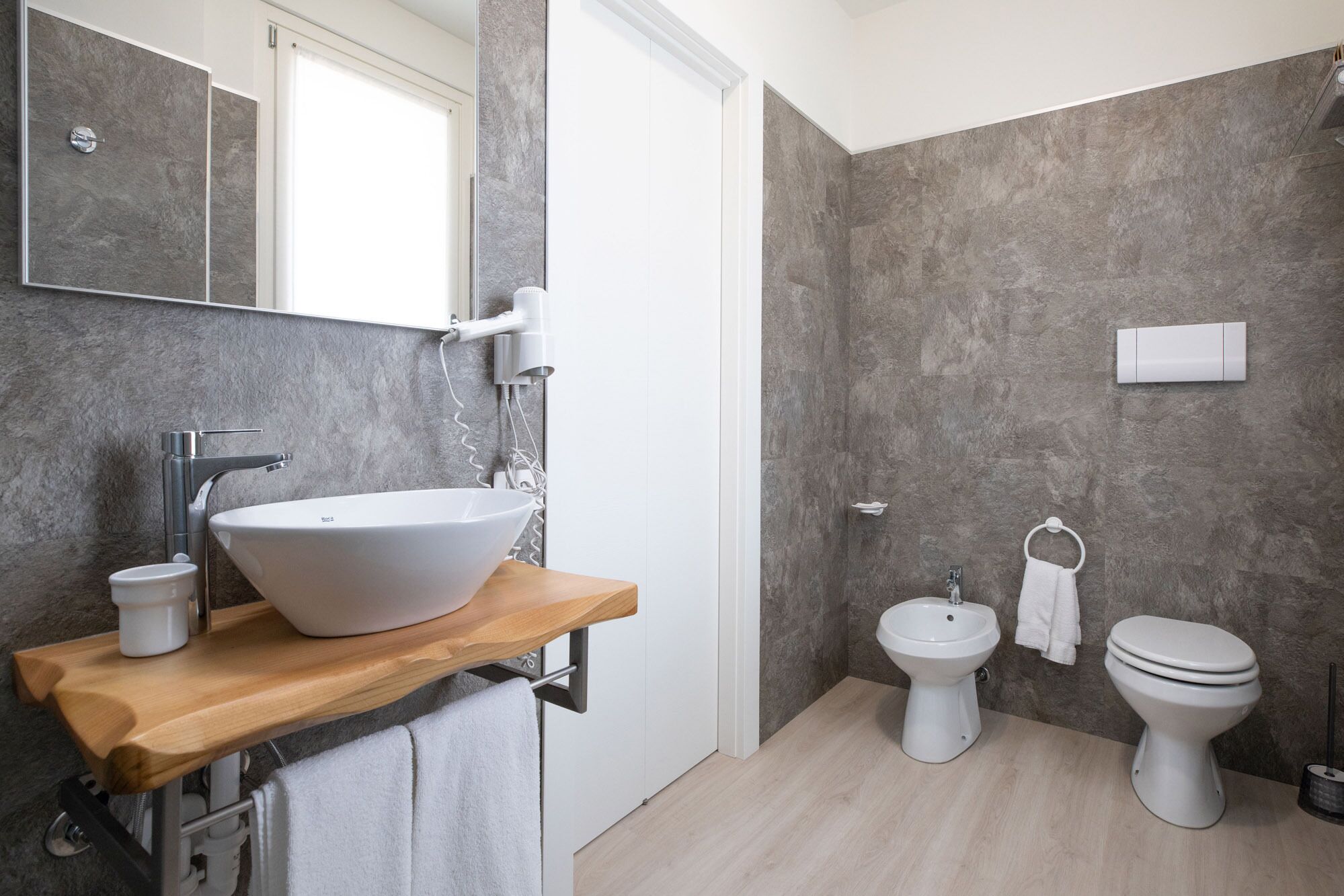 Un bagno moderno con un lavabo a incasso, un soffione doccia a mano, un bidet e un water.