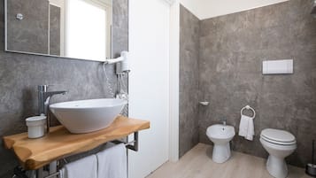 Un bagno moderno con un lavabo a incasso, un soffione doccia a mano, un bidet e un water.