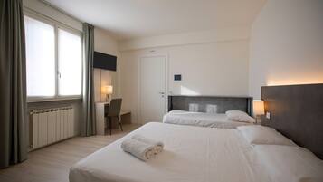Ein Hotelzimmer mit zwei Betten, einem Schreibtisch und einem Stuhl.