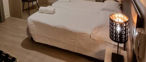 A hotel room with a bed, desk, chair, and two bedside lamps.