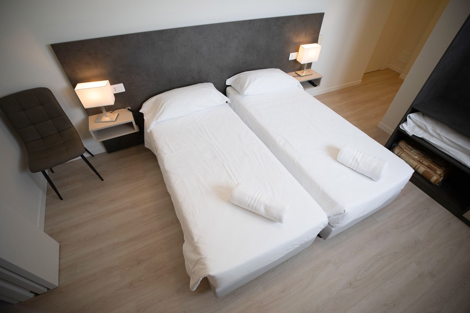 A double room with two beds, bedside lamps, a chair, and a TV.
