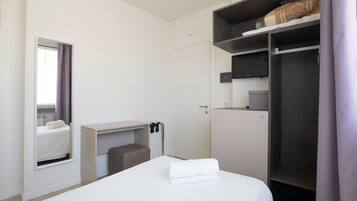 A hotel room with a bed, a desk, a wardrobe, and a bathroom.