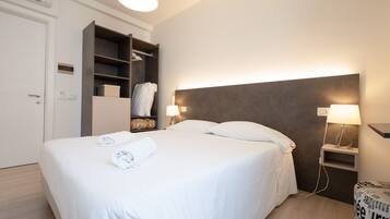 Ein Hotelzimmer mit einem Bett, zwei Nachttischen mit Lampen, einem Kleiderschrank und einer Wand-Klimaanlage.