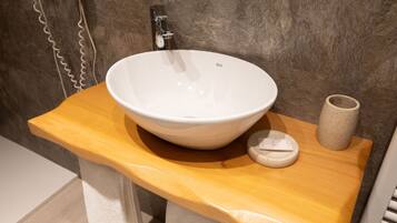 Un baño con un lavabo de cerámica blanca, un mueble de tocador de madera y un jarrón beige.