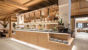 A modern kitchen with wooden cabinetry, a central island with a sink, and overhead pendant lighting. - Anewandter Historic Hotel (Gais)