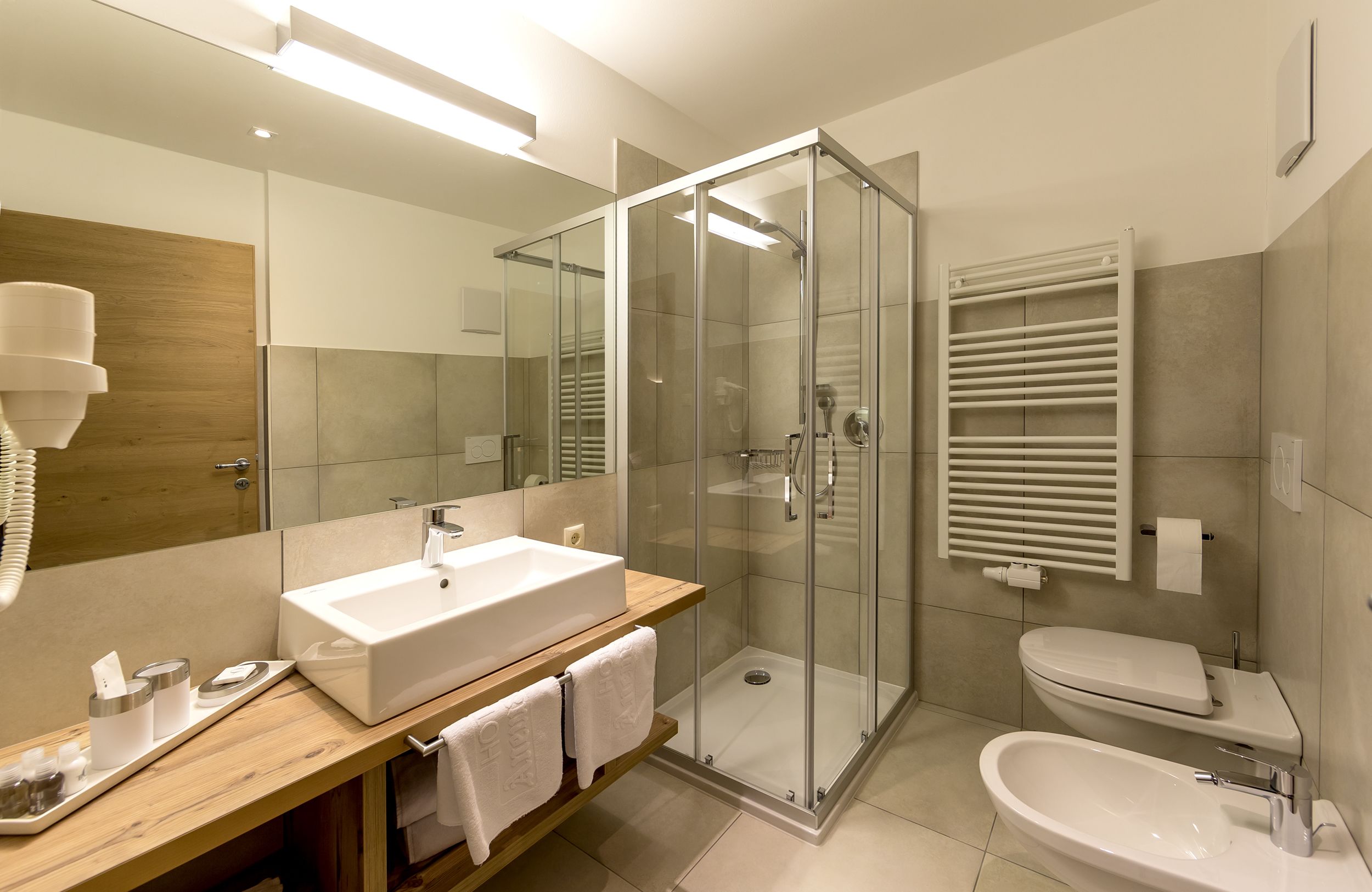 A modern bathroom with a glass-enclosed shower, a white sink, and a toilet.