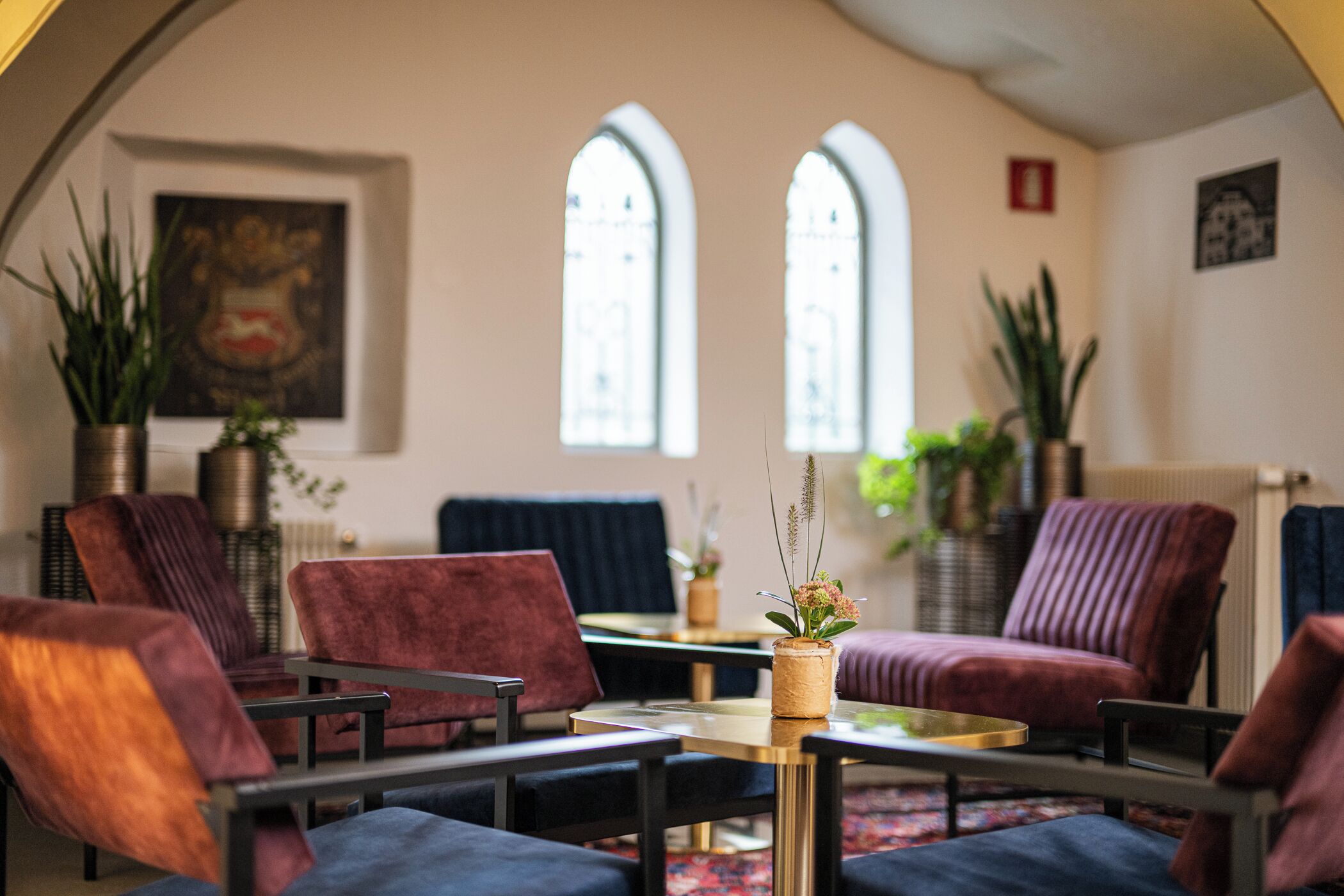 Una habitación con sofá, sillones, una mesita y plantas en macetas.