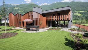 A modern building with a patio area, a stone pathway, and a view of mountains. - Anewandter Historic Hotel (Gais)