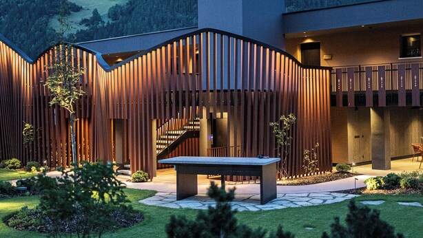 A modern building with a curved facade, outdoor seating, and a view of mountains. - Anewandter Historic Hotel (Gais)