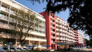 A multi-story hotel with balconies, outdoor seating, and a red and white facade. - Gladiola Star (Golden Sands)